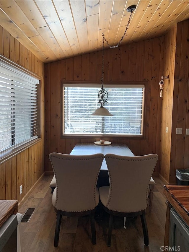 dining area featuring hardwood / wood-style flooring, wooden ceiling, and wood walls