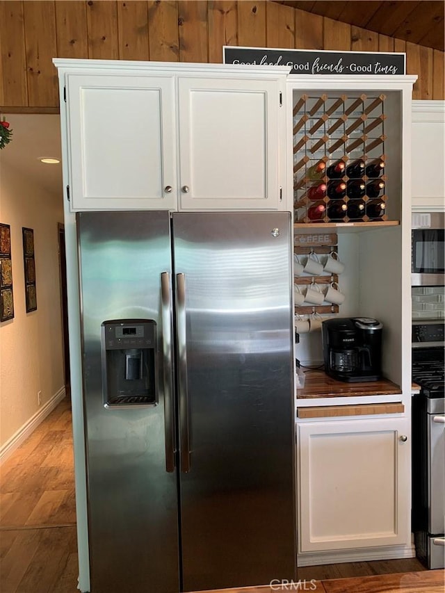 kitchen featuring lofted ceiling, white cabinets, and stainless steel appliances