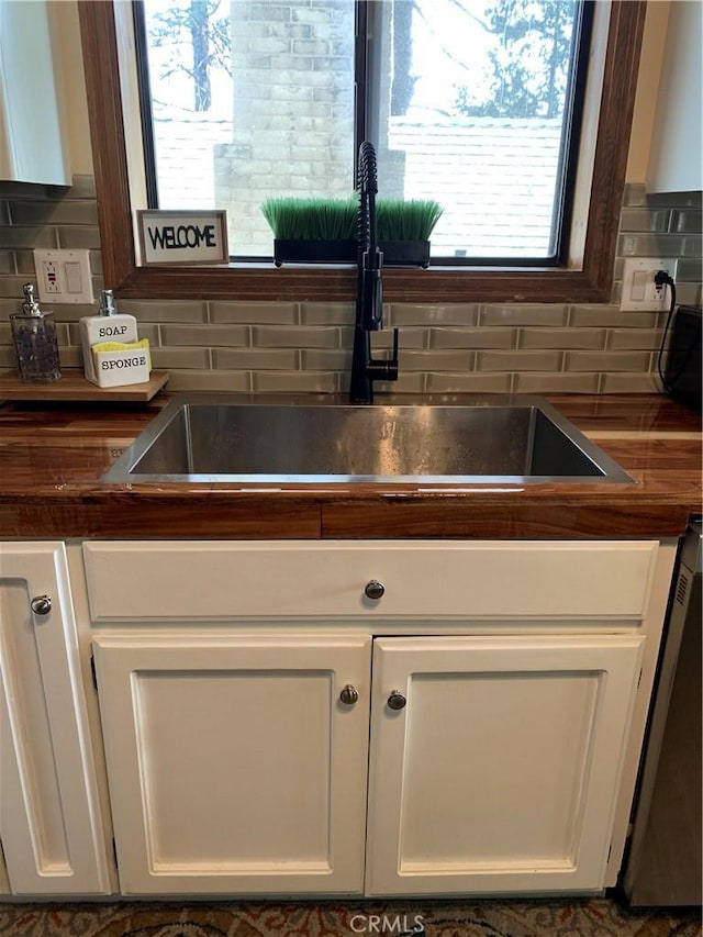 kitchen featuring sink, white cabinets, dishwasher, and tasteful backsplash