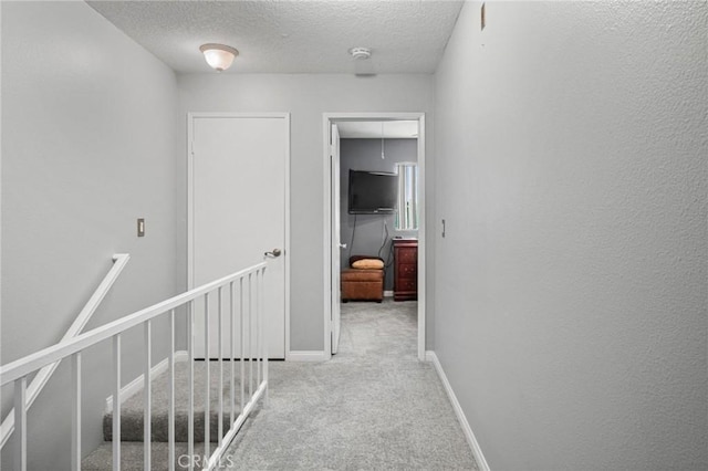 hallway with light carpet and a textured ceiling