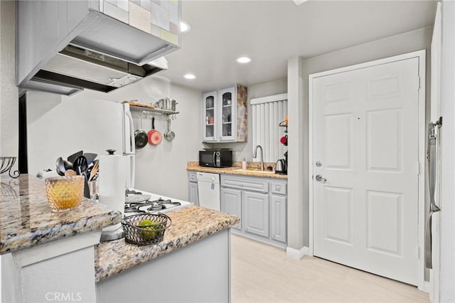 kitchen with sink, white appliances, extractor fan, and light stone counters