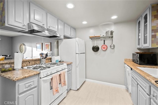 kitchen with white cabinetry, light stone countertops, and white appliances