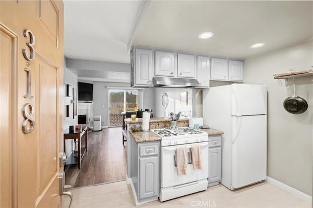 kitchen with gray cabinetry, light stone countertops, light hardwood / wood-style flooring, and white appliances