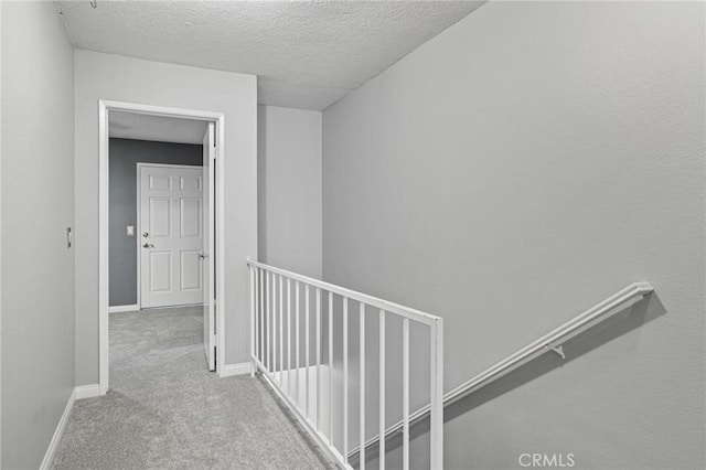 hallway with light carpet and a textured ceiling