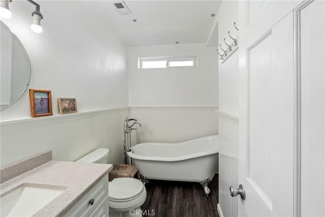 bathroom with hardwood / wood-style flooring, vanity, toilet, and a tub to relax in