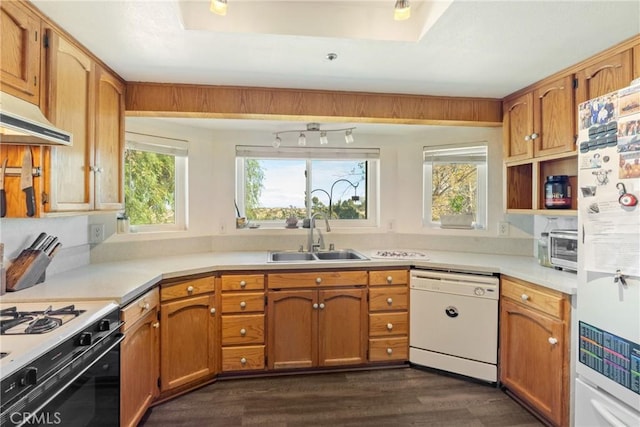 kitchen featuring wall chimney range hood, dark hardwood / wood-style flooring, sink, and white appliances