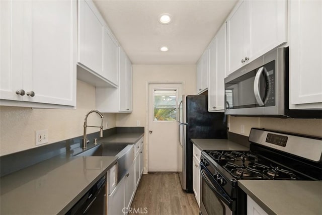 kitchen with stainless steel appliances, dark countertops, white cabinets, and a sink