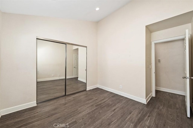 unfurnished bedroom featuring a closet, baseboards, dark wood-style flooring, and recessed lighting