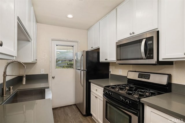 kitchen with appliances with stainless steel finishes, a sink, and white cabinetry