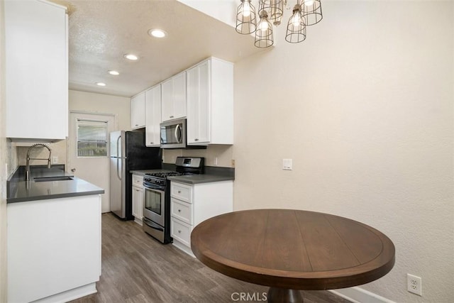 kitchen with stainless steel appliances, dark countertops, white cabinets, and a sink