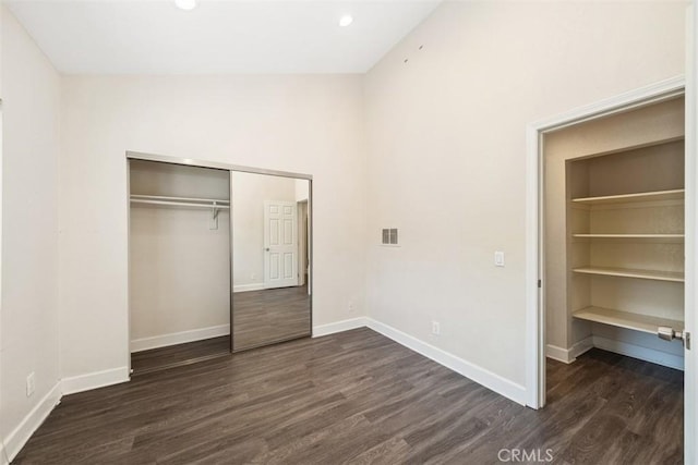 unfurnished bedroom with a closet, visible vents, dark wood finished floors, and baseboards