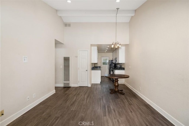 unfurnished dining area featuring baseboards, visible vents, dark wood-type flooring, and beam ceiling