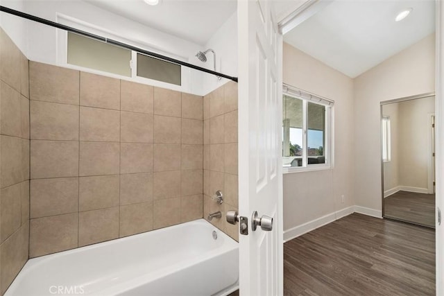 bathroom with lofted ceiling, wood finished floors, bathing tub / shower combination, and baseboards