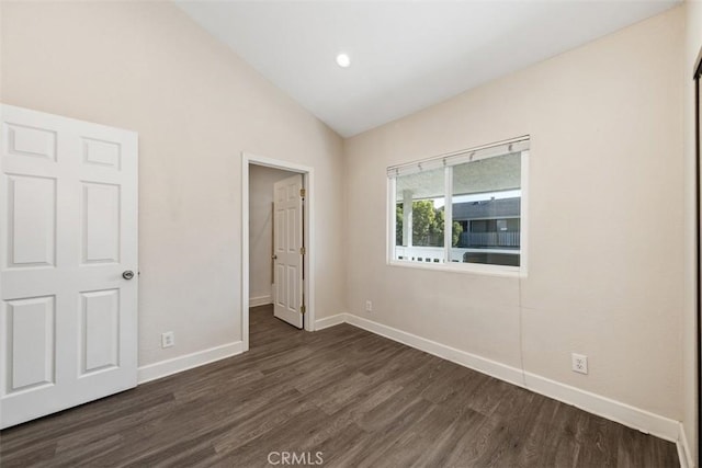 unfurnished bedroom featuring lofted ceiling, dark wood finished floors, and baseboards