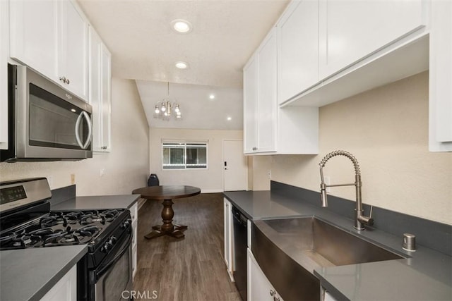 kitchen with dark countertops, white cabinets, stainless steel appliances, and a sink