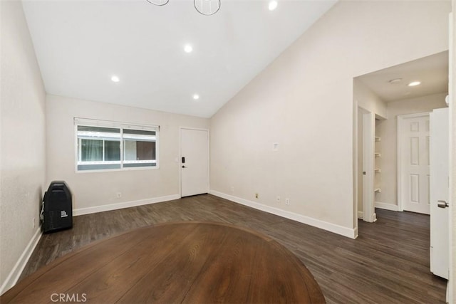 interior space featuring dark wood-style floors, baseboards, vaulted ceiling, and recessed lighting