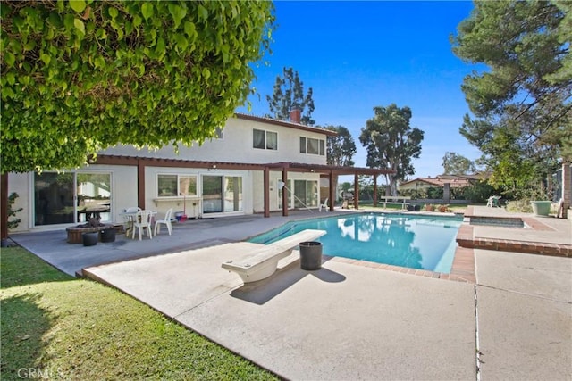 view of swimming pool with a patio area, a diving board, a fire pit, and a hot tub