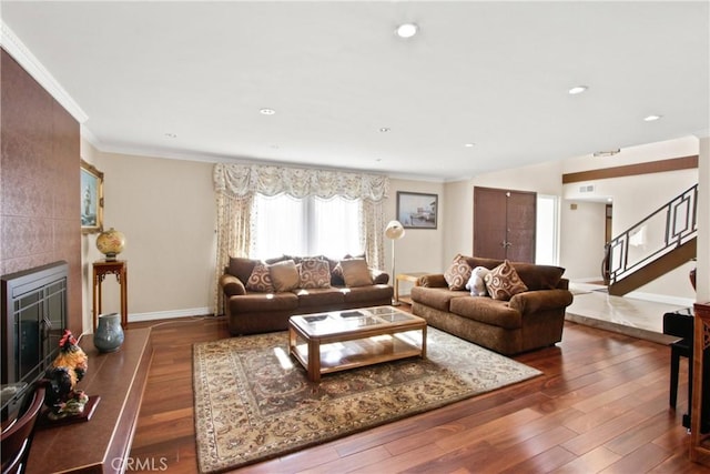 living room with dark hardwood / wood-style floors, ornamental molding, and a fireplace