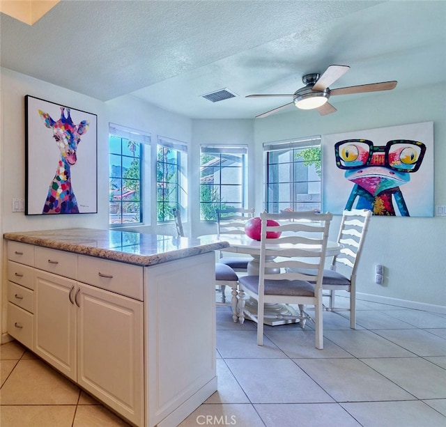 kitchen featuring white cabinetry, a wealth of natural light, light tile patterned flooring, and a textured ceiling