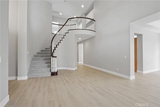 interior space with a towering ceiling and light wood-type flooring