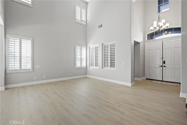 entrance foyer with a chandelier, a towering ceiling, and light hardwood / wood-style floors