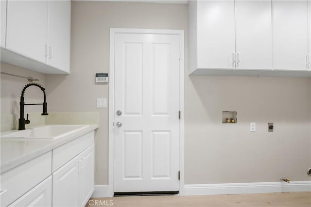 washroom featuring cabinets, washer hookup, electric dryer hookup, sink, and light hardwood / wood-style flooring