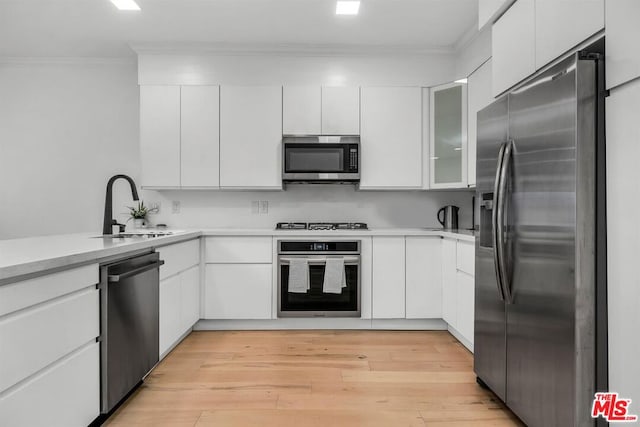 kitchen featuring white cabinets, light wood-type flooring, and appliances with stainless steel finishes