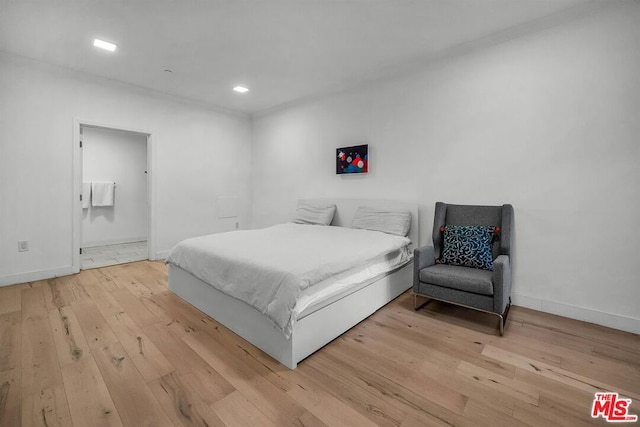 bedroom with ensuite bath and light hardwood / wood-style flooring