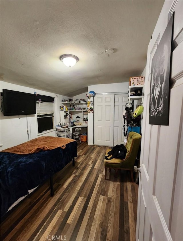 bedroom with dark hardwood / wood-style floors, a textured ceiling, and vaulted ceiling