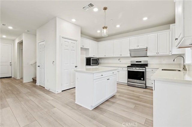 kitchen featuring hanging light fixtures, sink, light hardwood / wood-style floors, appliances with stainless steel finishes, and a kitchen island