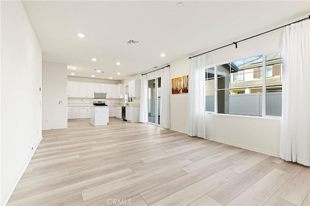 unfurnished living room with light wood-type flooring and sink