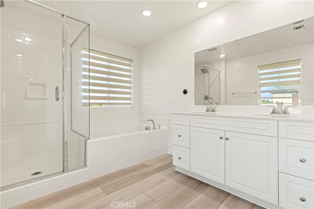 bathroom with separate shower and tub, vanity, and wood-type flooring