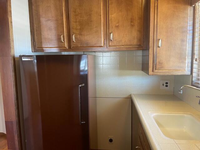 interior space featuring backsplash, sink, and stainless steel refrigerator