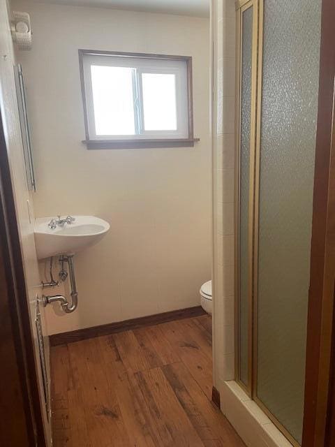 bathroom featuring hardwood / wood-style flooring, toilet, and walk in shower