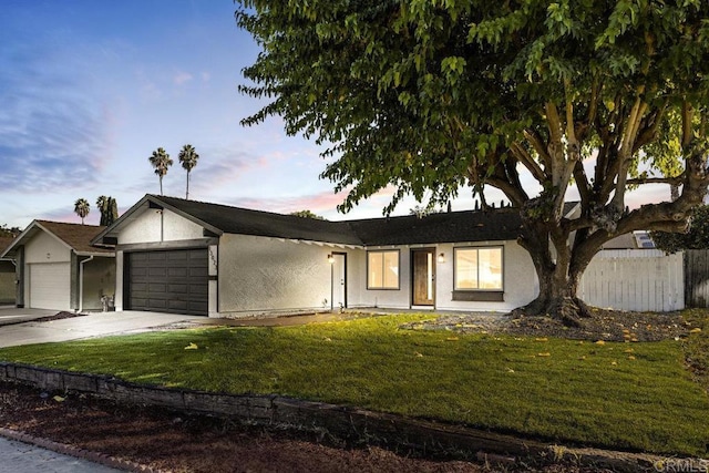 ranch-style home featuring a garage and a lawn