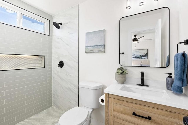 bathroom with toilet, vanity, ceiling fan, and a tile shower