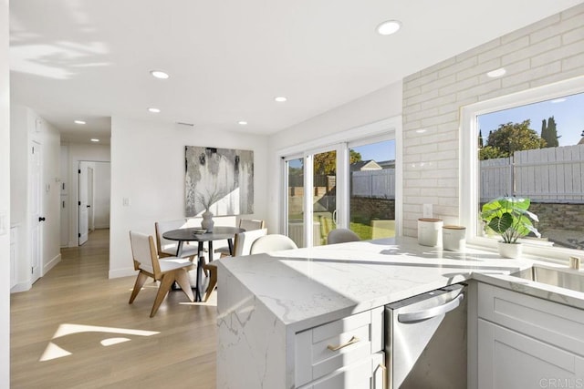 kitchen with light stone counters, white cabinetry, and light hardwood / wood-style floors