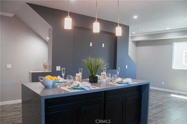 kitchen with hanging light fixtures, a center island with sink, and dark wood-type flooring