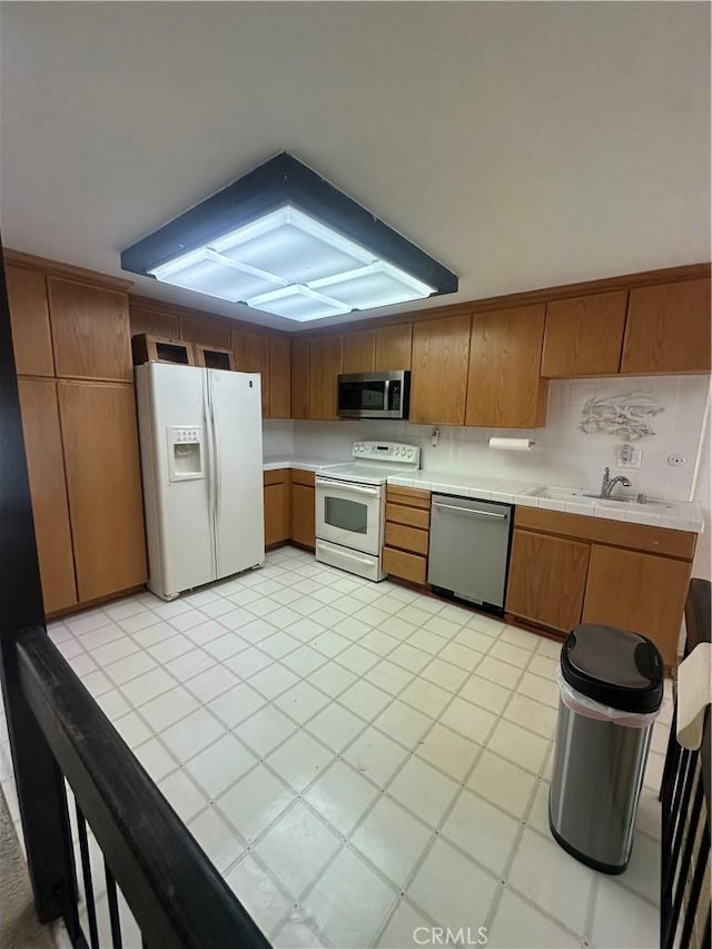 kitchen with tasteful backsplash, stainless steel appliances, tile countertops, and sink