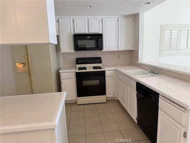 kitchen with tile countertops, white cabinetry, sink, and black appliances