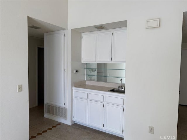 kitchen with white cabinets, light tile patterned flooring, and sink