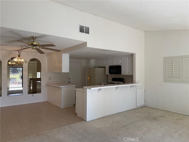 kitchen featuring kitchen peninsula, light carpet, a breakfast bar, black appliances, and white cabinetry