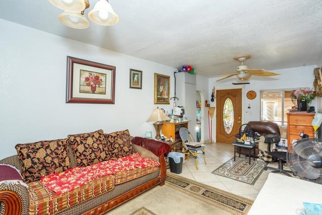 tiled living room featuring ceiling fan with notable chandelier and a textured ceiling