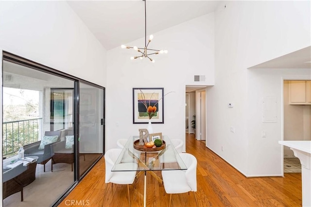 dining room featuring light wood-type flooring, an inviting chandelier, and high vaulted ceiling