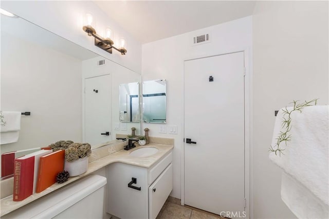 bathroom with toilet, vanity, and tile patterned flooring