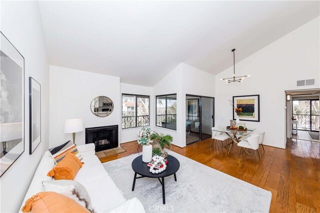 living room featuring high vaulted ceiling, hardwood / wood-style floors, and a notable chandelier