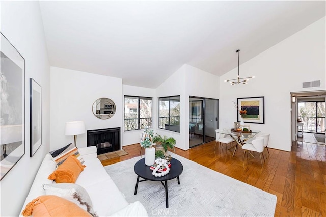 living room featuring high vaulted ceiling, wood-type flooring, and a chandelier