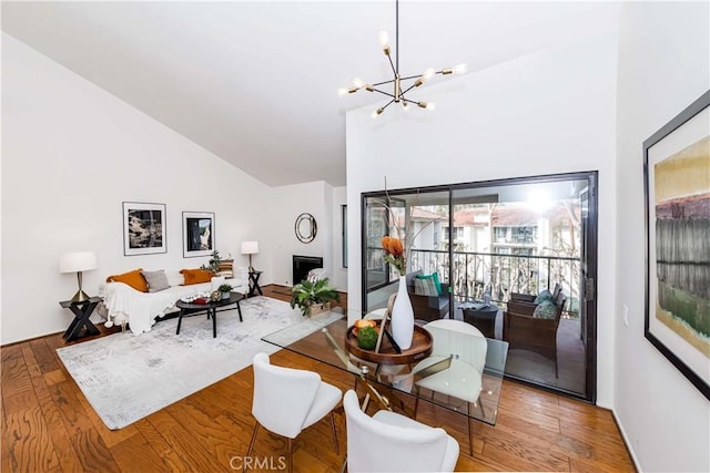 dining area with an inviting chandelier, hardwood / wood-style flooring, and high vaulted ceiling