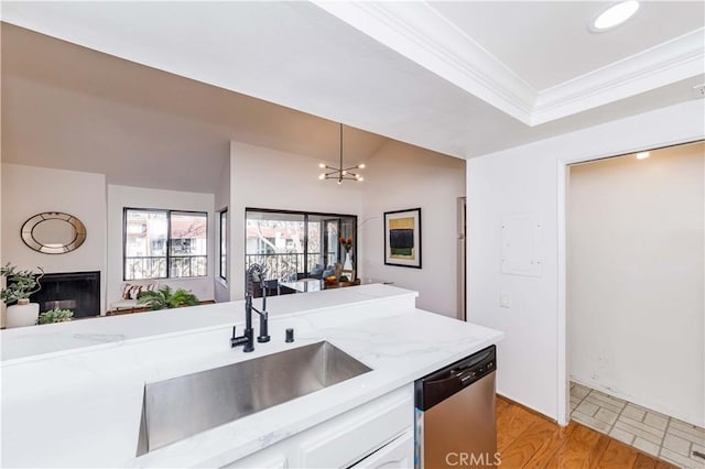 kitchen featuring a notable chandelier, pendant lighting, stainless steel dishwasher, white cabinets, and sink