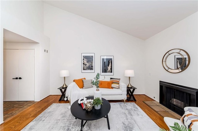 living room featuring wood-type flooring, a tile fireplace, and vaulted ceiling